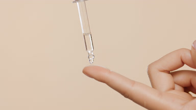 Clear serum is dripped from dropper on female forefinger