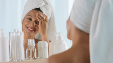 African woman strokes body and forehead in front of the mirror