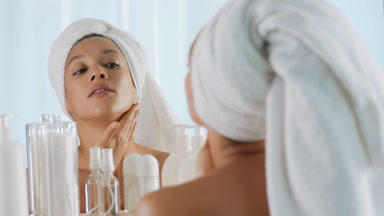 African woman rubs hands and strokes body in front of the mirror