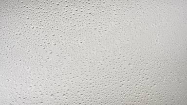 Medium size water drops blown off the glass surface on grey bg