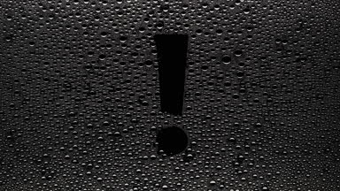 Exclamation sign blown off the wet glass on black background