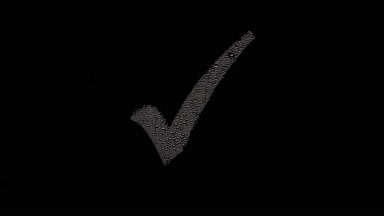 Checkmark blown off the wet glass on black background