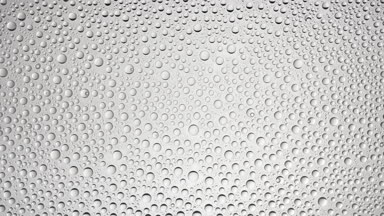Big size water drops blown off the wet glass surface on grey bg
