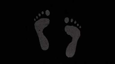Inverted footprints blown off the wet glass on black background