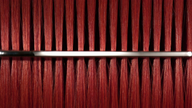 Red dyed hair being combed with silver comb