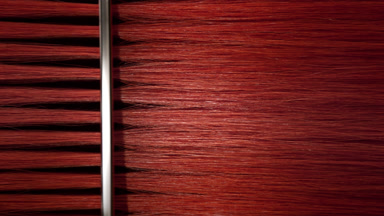Silver comb combing red dyed hair
