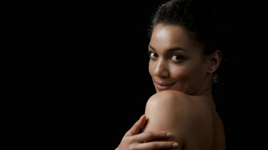 Woman strokes shoulder and arm turning to the camera smiling