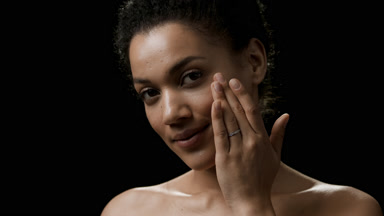 Pretty African young woman with dark curly hair strokes her face