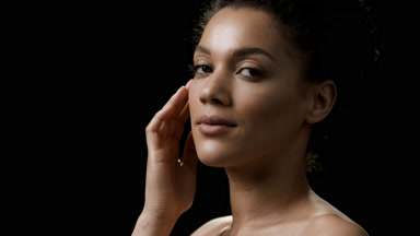 African young woman strokes her jaw line looking at the camera
