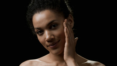 Beautiful African black-haired woman strokes her face smiling