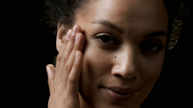African American young woman with black curly hair strokes face