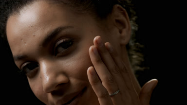 Young African cute woman with dark curly hair strokes her face