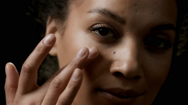 Brunette young African pretty woman strokes her face under eye