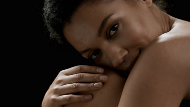 Attractive brunette African woman with curly hair strokes knee