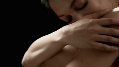 Beautiful young slim dark-haired African woman strokes her arm