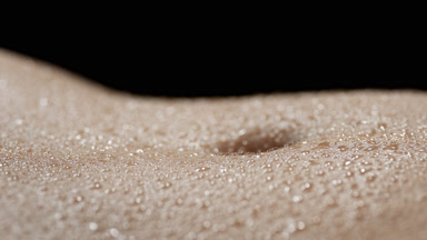 A lot of water drops on moving belly of African slim woman