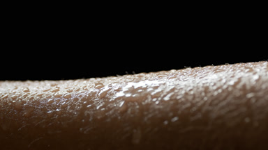 Water falls down on wet moving skin of African female model