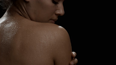 Slim African woman with black curly hair strokes wet shoulder