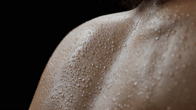 African female model with dark curly hair moves wet shoulders