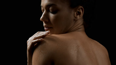 Dark-haired slim African American woman strokes her wet shoulder