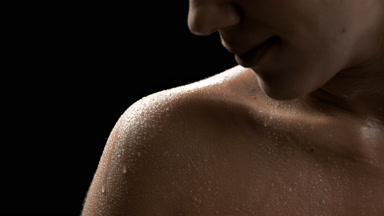 Brunette African American woman with wet shoulder moves her head