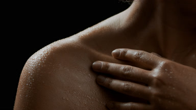 Young good-looking slim African woman strokes her wet clavicles