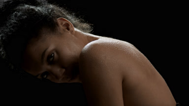 Woman with wet shoulders moves her head up looking at the camera