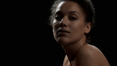 Woman with wet shoulders moves head up and looks at the camera