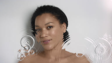 African woman looks at the camera smiling through rippling water