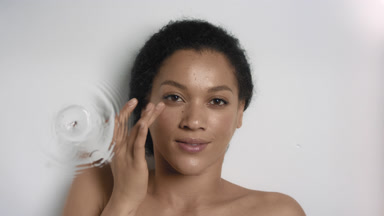 Woman strokes face under eye smiling wide through rippling water