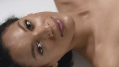 Dark-haired African woman looks at camera through rippling water
