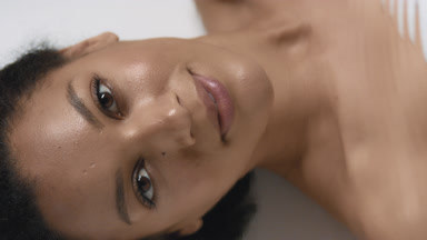 Pretty woman strokes clavicles and looks at camera through water