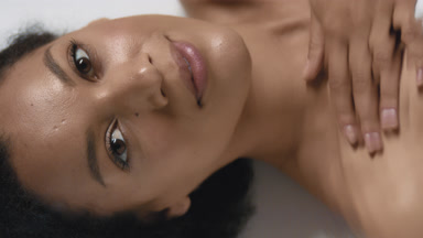 Cute woman strokes collarbones and looks at camera through water
