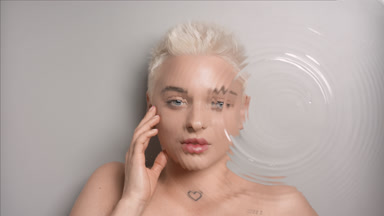 Pretty woman strokes face looking at the camera through water
