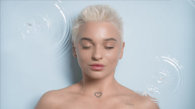 Woman opens eyes and looks at the camera smiling through water