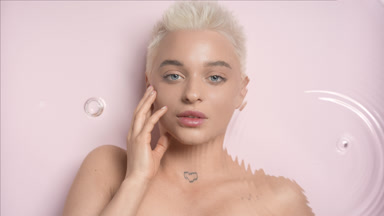 Pretty woman with short hair strokes face through rippling water