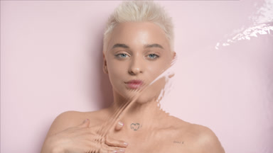 Woman strokes collarbones looking at the camera through water