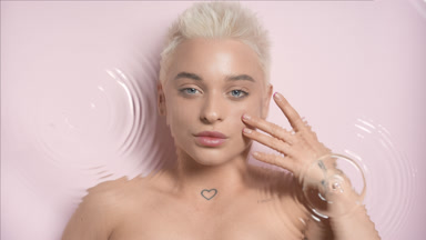 Woman strokes cheek looking at the camera through rippling water