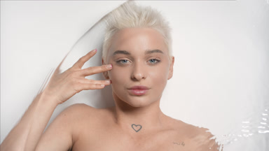 Woman strokes face under eye looking at camera through water