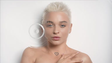 Woman strokes her clavicles looking at the camera through water