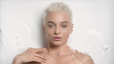 Pretty woman strokes collarbones smiling through rippling water