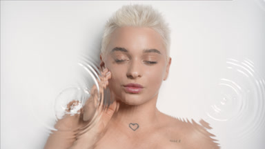 Caucasian woman strokes face looking at the camera through water