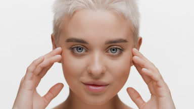 Beautiful blond woman moves head up touching face and smiles