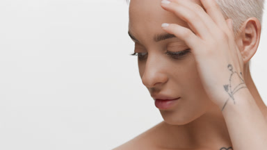 Young slim woman looks at the camera stroking face and smiling