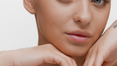 Young blonde Caucasian woman strokes face looking at the camera