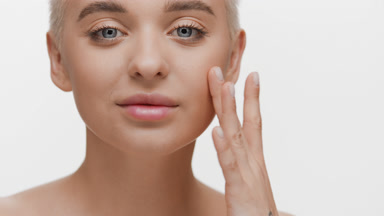 Cute young fair-haired Caucasian woman touches cheek tapping