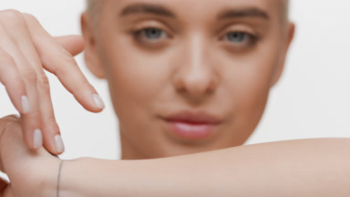 Cute slim fair-haired Caucasian woman strokes forearm and smiles