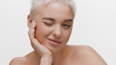 Young Caucasian woman winks at the camera resting head on hand