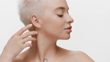 Cute fair-haired Caucasian woman strokes jawline turning head