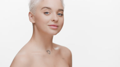 Slim woman with bare shoulders turns away from camera smiling